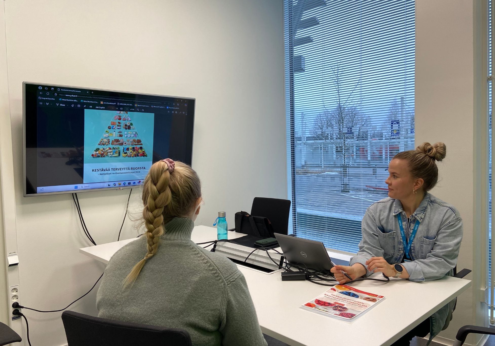 Kuvassa ravitsemusasiantuntija ohjaa yksilöä henkilökohtaisella ravitsemussuunnitelman kanssa. 